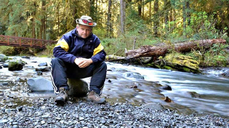 man sitting beside stream