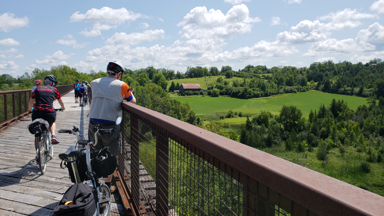 Man looking out over countryside from a rail trail bridge.