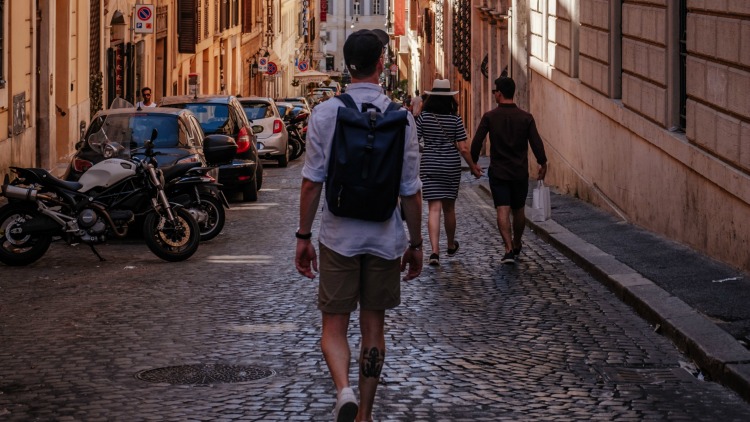 man walking on cobblestones, travel budget essentials