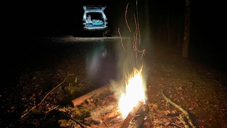 car camping alone in front of bonfire