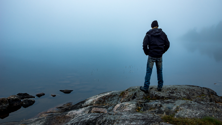 man standing alone on rock shows one of the solo travel myths: that you'll be lonely
