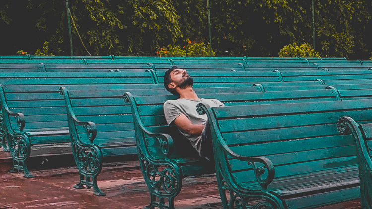 one of the myths about solo travel is that you'll be bored, like this man with his eyes closed on a bench