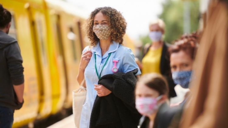 people waiting for train with masks on