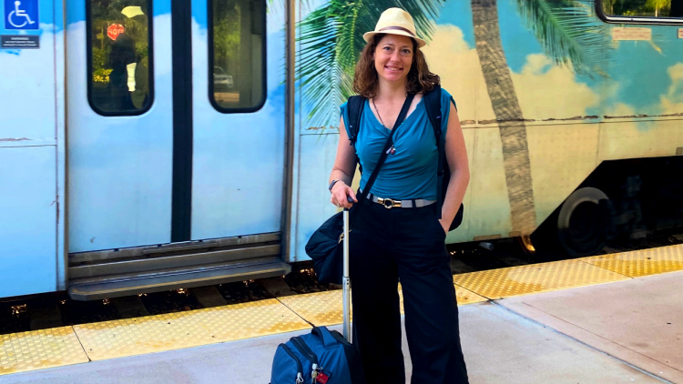Nora Dunn standing beside a train.