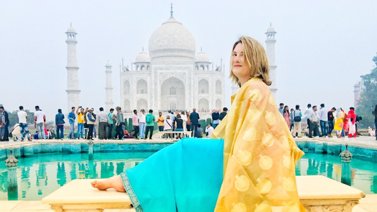 Mariellen Ward sitting on a bench near the Taj Mahal on a solo trip to India