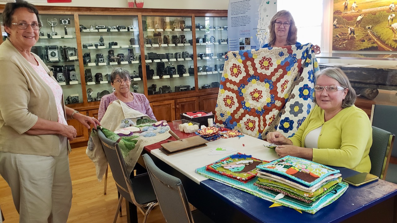 women of the acadian shores doing traditional rug hooking and quilting