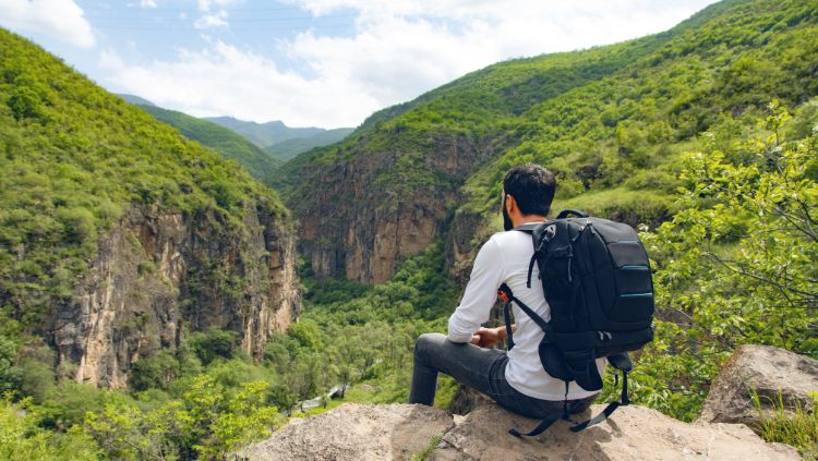 male solo traveler sitting on rock