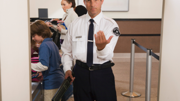 security officer gesturing for traveler to move ahead