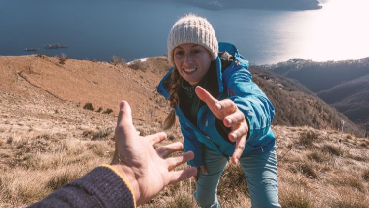 Woman reaching for a hand up on a hike