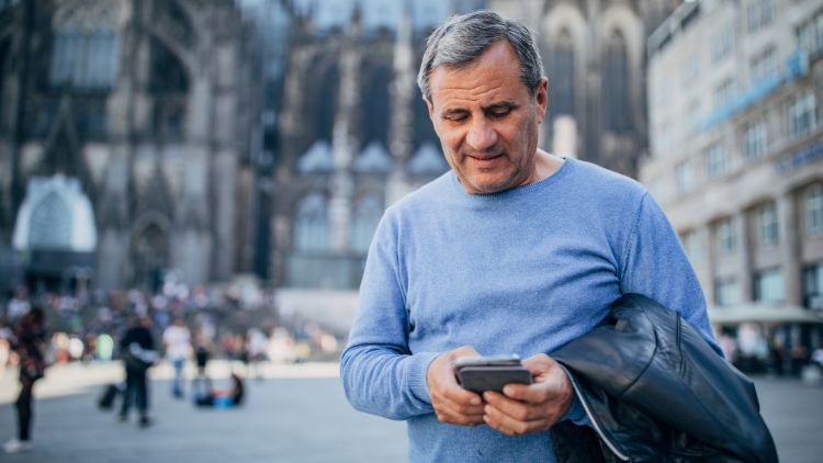 homem na praça da cidade usando seu telefone enquanto viaja