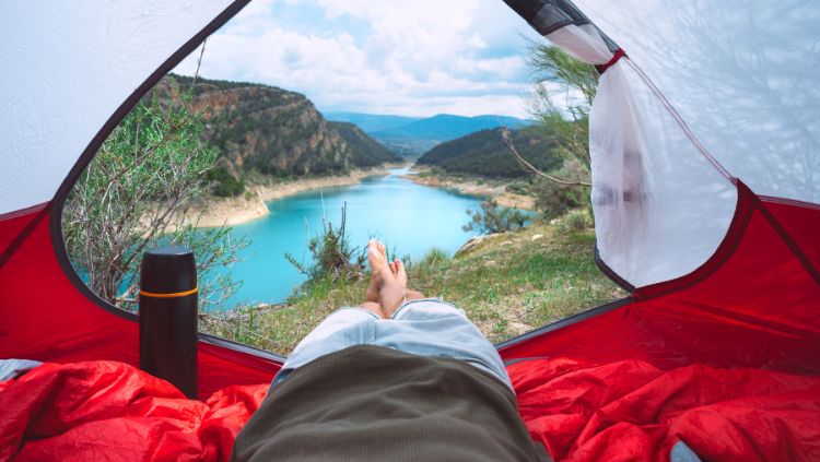 traveler laying in tent, looking out at landscape
