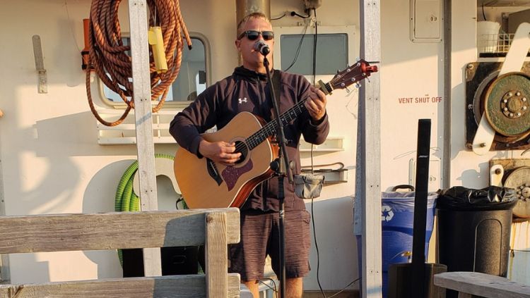 homem tocando violão e cantando no barco