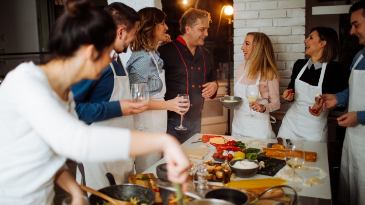 pessoas reunidas em torno de uma mesa em uma aula de culinária