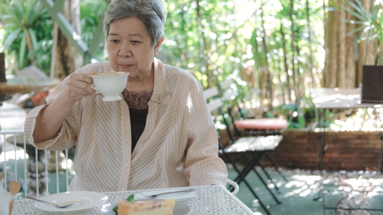 older woman eating alone in outdoor cafe