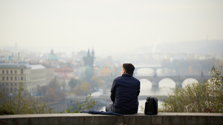 Man looking out over city, traveling solo for healing