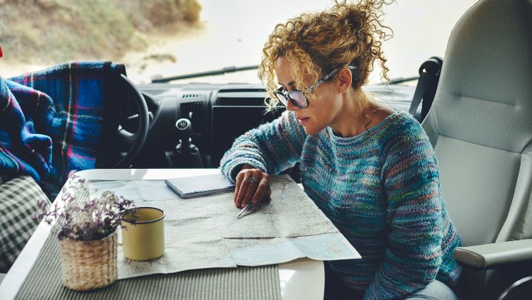 woman traveling alone, reading map in an RV