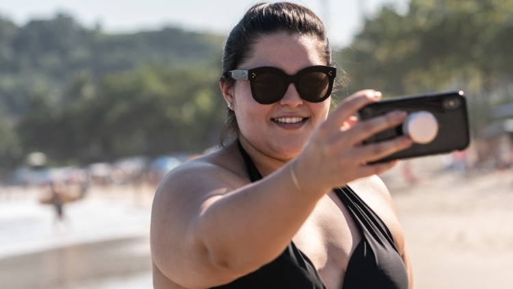 woman taking a selfie on a beach while going to a resort alone