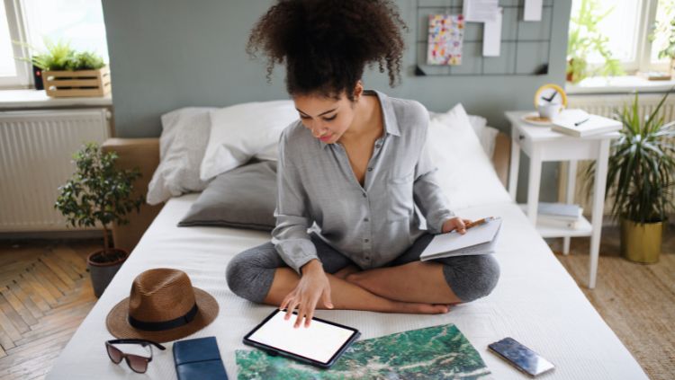 woman sitting on bed making travel plans