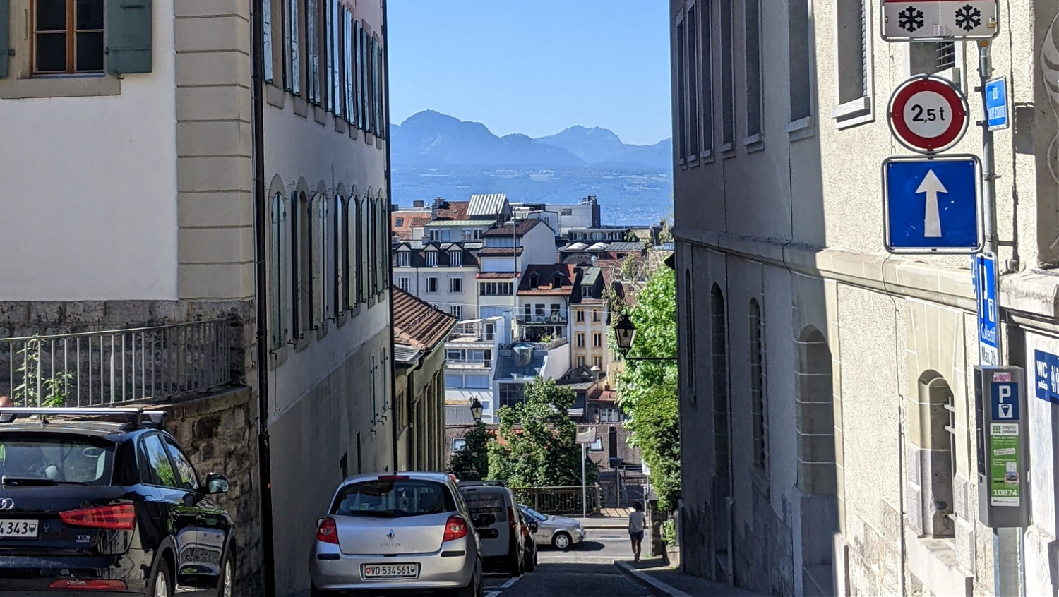 a pretty street in downtown Lausanne with mountains in the distance